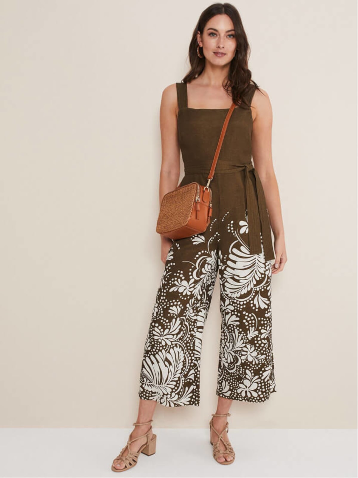 Woman wearing printed wide leg jumpsuit with a brown bag and brown sandals