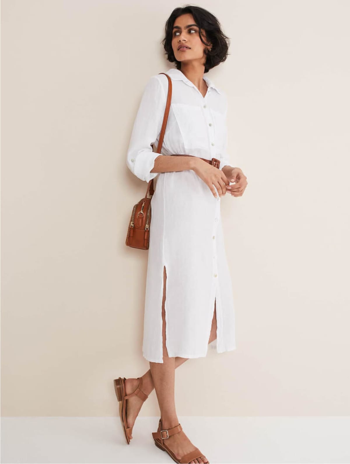 Woman wearing white linen shirt dress with brown bag and brown sandals