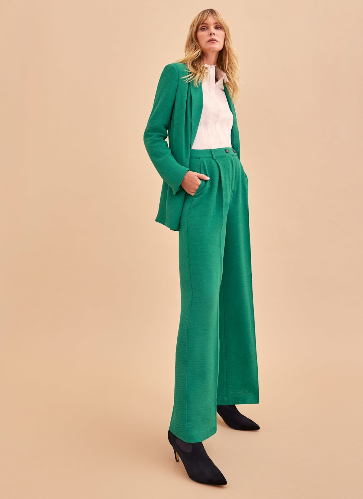 Woman wearing green suit co-ord and black boots