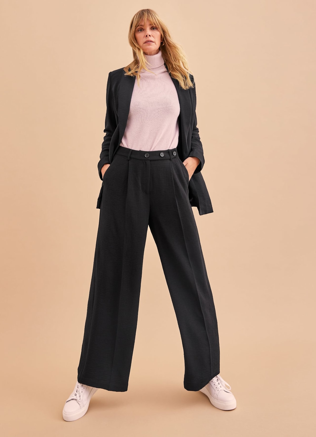 Woman modelling black suit co-ord with trainers