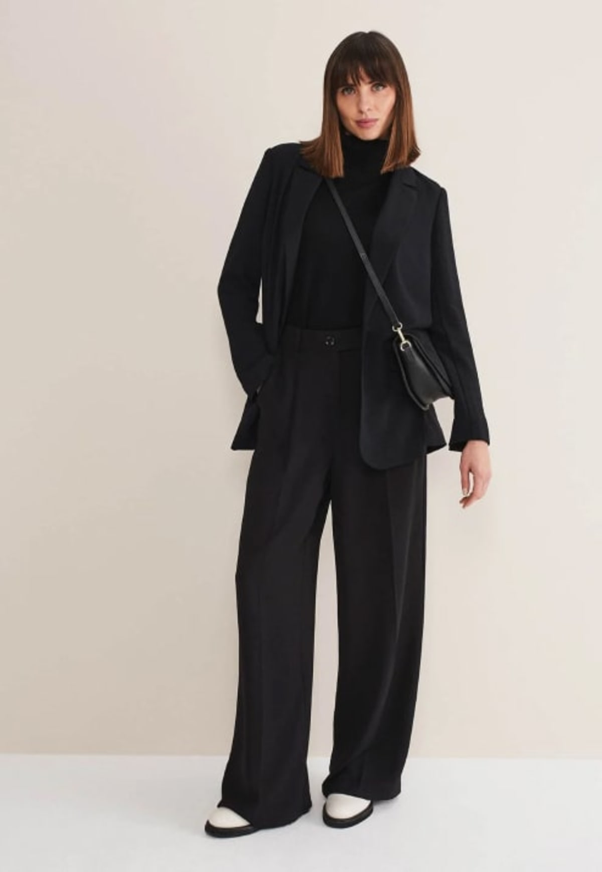 Woman wearing black suit co-ord with black handbag