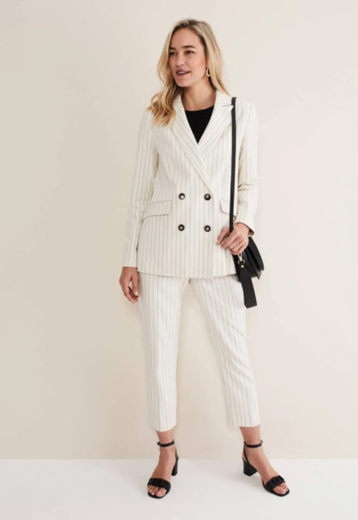 Woman wearing striped suit blazer with white jeans and brown sandals