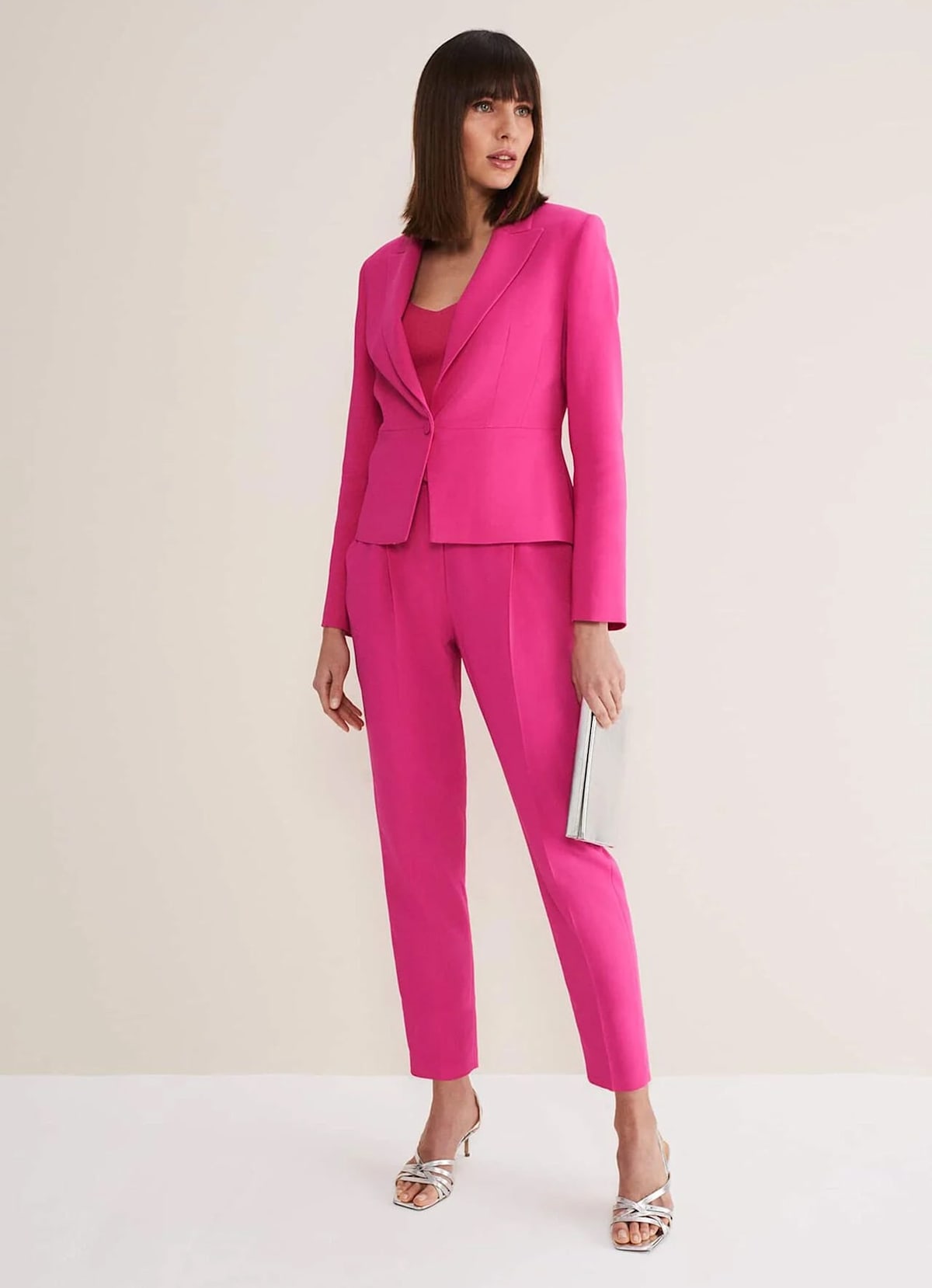 Woman wearing pink suit co-ord with silver heels and silver clutch