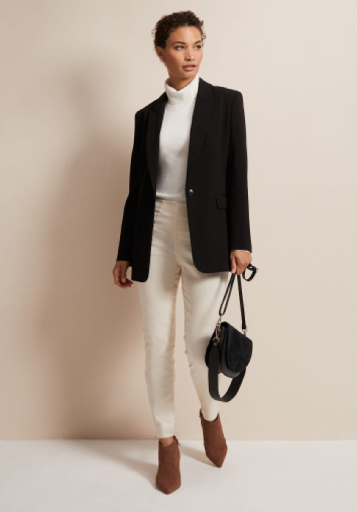 Woman wearing Phase Eight black blazer and cream jeggings